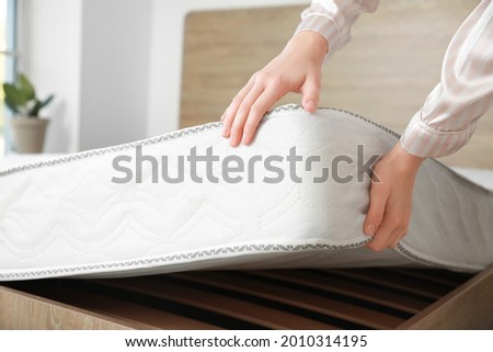 Woman putting soft orthopedic mattress on bed Royalty-Free Stock Photo #2010314195