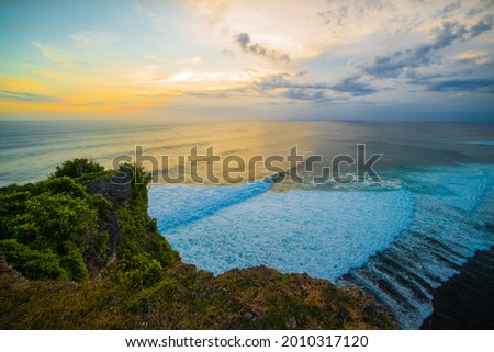 Breathtaking seascape. Spectacular view from Uluwatu cliff in Bali. Sunset time. Blue hour. Ocean with motion foam waves. Waterscape for background. Nature concept. Soft focus. Slow shutter speed.