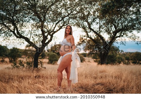 Young girl about to have a baby in nature taking pictures in her underwear