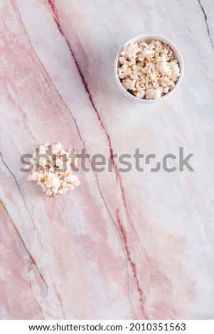 White bowl with popcorn on white and red marble. Documentaries or gastronomic films.