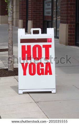 A sign reading Hot Yoga outside on the sidewalk
