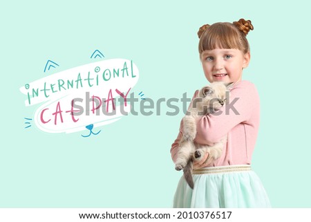 Girl with cute fluffy kitten on color background. International Cat Day Royalty-Free Stock Photo #2010376517