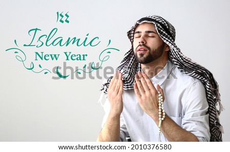 Young Muslim man praying on light background. Celebration of Islamic New Year Royalty-Free Stock Photo #2010376580