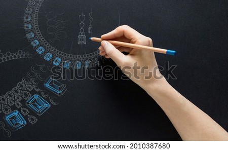 Jewellery theme. A hand with a pencil draws a picture with jewelry. Royalty-Free Stock Photo #2010387680