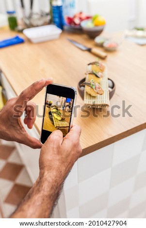 Anonymous man taking a picture with smartphone of nigiri for social media and sharing with friends