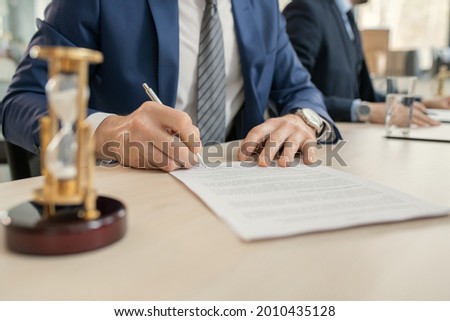 Close-up of businessman sitting at the table and signing a contract during a business meeting at office