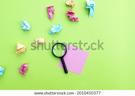 Top view photo of a magnifying glass and blank sticker on a green background. Copy space.