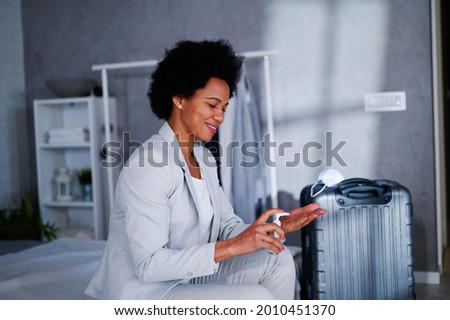 Black ethnicity businesswoman, arrived at her hotel room, putting disinfectant gel on her hands