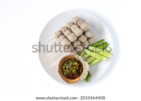 Meatballs on skewers, meatballs, noodles with vegetables, and a cup of dipping sauce Food for grilling, frying, steaming, placed on a plate and white background.