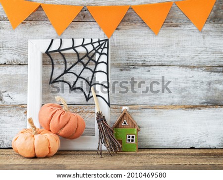Halloween background with pumpkins, web, small house, broom and garland of flags on a wooden surface