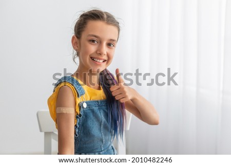 Effective Covid Vaccine Against New Delta Variant. Portrait Of Cheerful Smiling Adolescent Patient Showing Vaccinated Arm With Sticking Patch On Her Shoulder After Getting Shot And Thumb Up Gesture Royalty-Free Stock Photo #2010482246