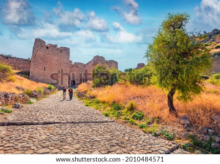 Tourists rising up to popular tourist destination - Acrocorinth fortress. Sunny summer scene of Greece, Europe. Traveling concept background. Royalty-Free Stock Photo #2010484571