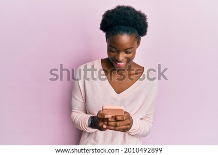 Young african american girl using smartphone smiling and laughing hard out loud because funny crazy joke. 