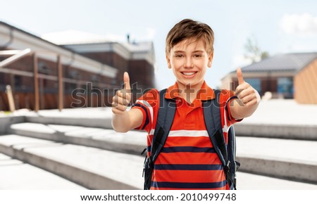 school, education and people concept - smiling student boy with backpack showing thumbs up over city street background