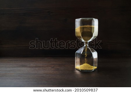 Hourglass on dark wooden background. Time concept.