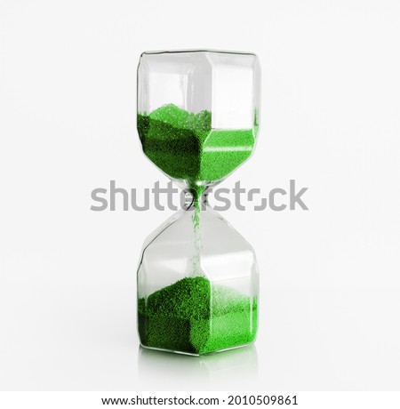Hourglass with green filler on light background. Time concept.