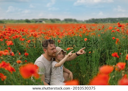 Happy father's day. Little boy and father are playing in a beautiful field of red poppies.