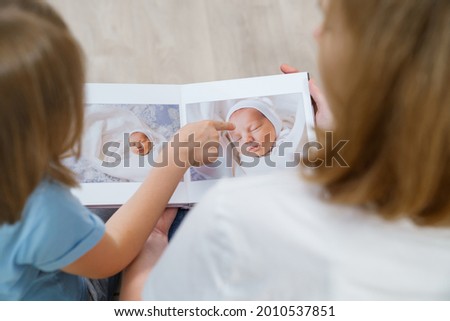 top view. mother and daughter watch photobook from discharge of newborn baby.family tradition of printing photos and looking at them with children and remembering.photographer and designer