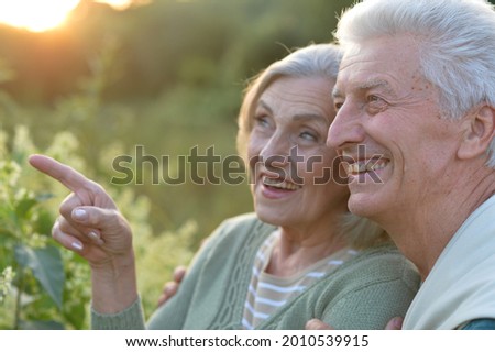 Close up portrait of senior couple posing in the park, man pointing with finger