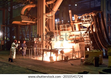 Workers in protective equipment in a foundry during the production of steel components - workplace industrial factory 
