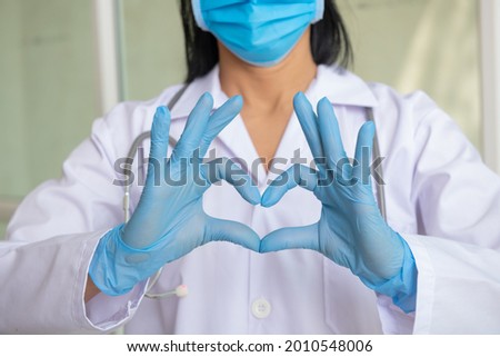 Doctors, infectionist,research and covid 19 concept.Woman with a medical mask and hands in latex glove shows the symbol of the heart. Doctor for the heart. Love to your pancreas. medical professionals