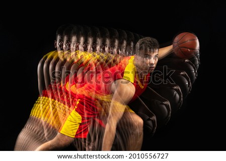 Dribbling the ball. Young basketball player training with ball isolated on dark background with stroboscope effect. Concept of professional sport, hobby. Energetical and dynamic.