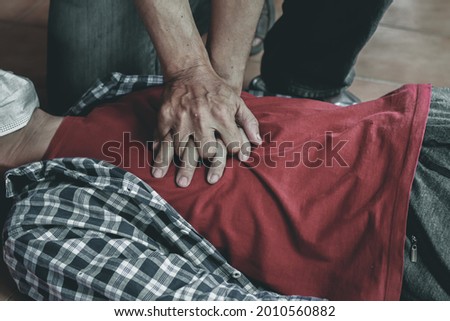 young man is helping his unconscious friend and stop breathing on the floor with CPR. Because the young man had trained to help patients with sudden cardiac arrest or CPR Cardiopulmonary Resuscitation Royalty-Free Stock Photo #2010560882