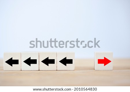 One red wooden block and black arrows to show concept move on, think different and individual standing out from the crowd and unique think different.