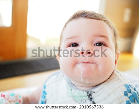 Ipswich, MA. A seven month old infant with a bib on and spit-up on his chin. Royalty-Free Stock Photo #2010567536