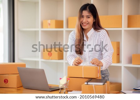Starting Small business entrepreneur SME freelance,Portrait young woman working at home office, BOX,smartphone,laptop, online, marketing, packaging, delivery, SME, e-commerce concept