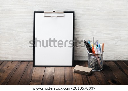 Photo of stationery set. Clipboard with blank letterhead, cup holder with pencils and pens, business cards. Copy space for text.