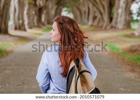 Rear view of a young woman with a backpack in the Cypress Tree Tunnel near San Francisco, USA