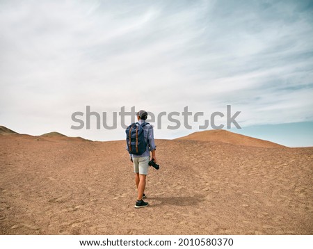 asian male backpacker landscape photographer walking on a hill looking at view, rear view