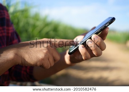 The farmer holds a smartphone and touches the screen to connect the intelligent management system within the farm. smart farmers research and market information online. Royalty-Free Stock Photo #2010582476