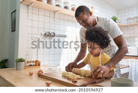 African American Father and son baking at home together. Black Child enjoying helping Dad. Brazilian family in the kitchen. Royalty-Free Stock Photo #2010596927