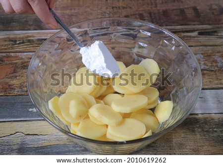 In the picture, we display a tablespoon of corn starch adding to a slice of potatos to make crispy french fries