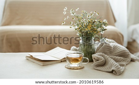 Still life with a cup of herbal tea, a bouquet of wildflowers, a book and a knitted element. Royalty-Free Stock Photo #2010619586