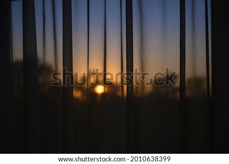 The sunset through the tulle on the window. Contour evening dusk light. Mesh fabric texture with sun glare. Royalty-Free Stock Photo #2010638399