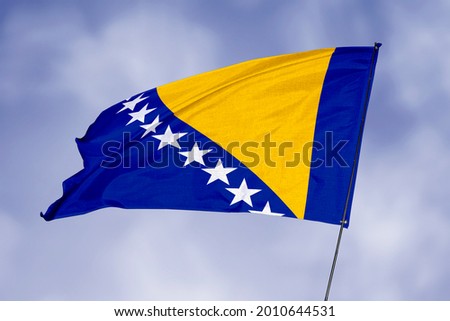 Bosnia and Herzegovina flag isolated on sky background. National symbol of Bosnia and Herzegovina. Close up waving flag with clipping path.