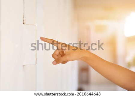 Student is using his hand to turn off the light switch in front of his class before going back home, soft and selective focus, sunlight edited background.
