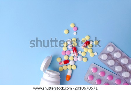 Colored tablets in bulk and in blisters on a blue background flat lay. Medicine, pharmaceuticals concept. Stock photography with copy space, selective focus. 