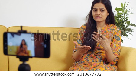 A beautiful Indian female is recording a video at home