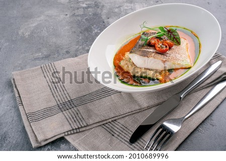Fried fish fillet of halibut on a plate with tomato sauce. Cod steak or white fish with sauce and herbs