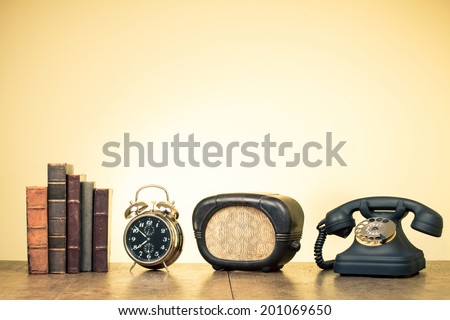 Vintage books, alarm clock, old radio, retro telephone on wood table
