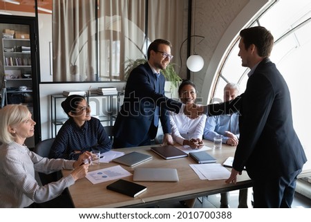 Employer, hr managers welcoming new employee to team, giving handshake to candidate at job interview. Diverse group of clients thanking professional for help, leader shaking hand on meeting Royalty-Free Stock Photo #2010700388
