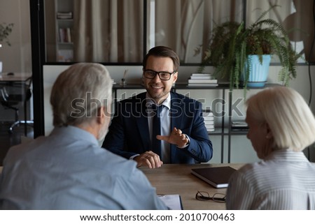 Happy confident lawyer, realtor, notary, financial advisor giving consultation, legal advice to senior couple of clients about medical insurance, wills, house buying or selling, savings, investment Royalty-Free Stock Photo #2010700463