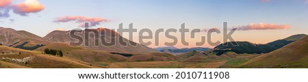 Sunset over blooming cultivated fields, famous colourful flowering plain in the Apennines, Castelluccio di Norcia highlands, Italy. Agriculture of lentil crops.