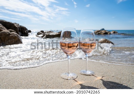 Summer time in Provence, two glasses of cold rose wine on sandy beach near Saint-Tropez in sunny day, Var department, France Royalty-Free Stock Photo #2010742265