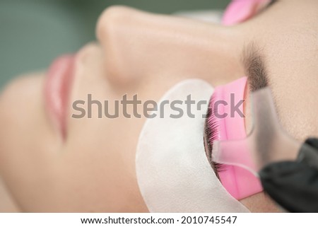 Master glues eyelashes to lash roller by applicator. Close-up of beauty model's face during lash lift laminating botox procedure. Eyelash Care Treatment: lifting and curling, lash lamination