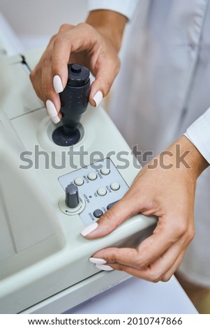 Female optometrist using modern equipment in clinic